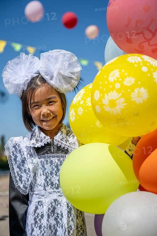 Happy schoolgirl with colourful balloons on the first day of school, Issyk-Kul region, Kyrgyzstan