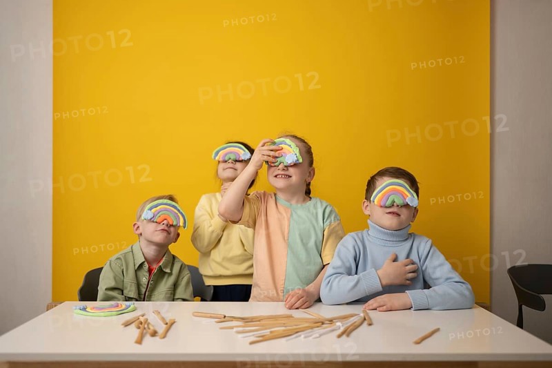 Children engage in a vibrant lesson, creatively using rainbow props to stimulate imagination and fun. The colorful setting encourages playful learning and collaboration