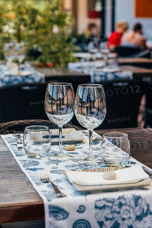 Set of glasses with white wine and plates placed on table with tablecloth on table