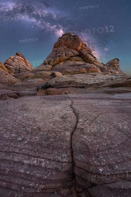 Captivating image of rugged desert rock formations beneath a vibrant Milky Way in Coyote Buttes, Arizona. The clear night sky enhances the texture and depth of the weathered landscape