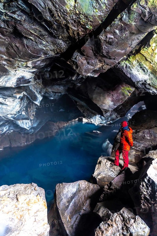 A man in the Grjotagja volcanic cave with hot thermal water near Lake Myvatn, Iceland