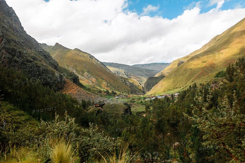 This image captures a breathtaking view of a green and fertile valley nestled in the Peruvian Andes