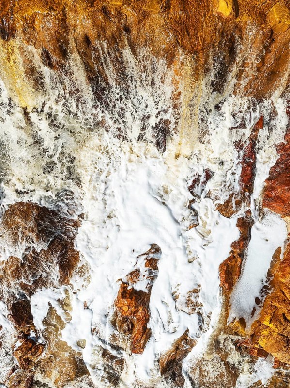 Detail of a waterfall in the Rio Tinto (Red river) with its orange-red hue due to oxidised iron minerals. Aerial view. Drone shot. Huelva province, Andalusia, Spain