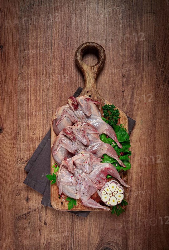 Raw quail meat, on a cutting board, with spices and herbs, top view