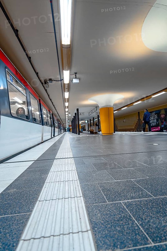 Close-up of an underground railway track with incoming train and bright lighting, Hamburg, Germany