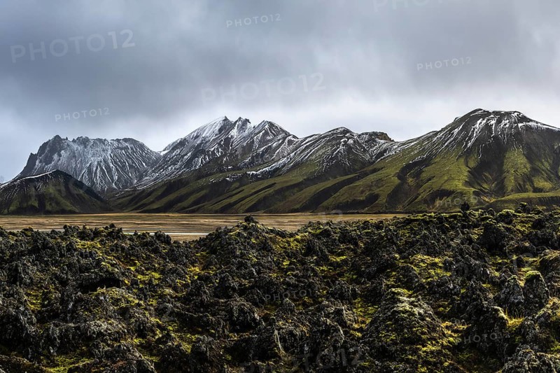 Experience the raw beauty of Iceland's Highlands, featuring rugged snow-capped mountains and lush mossy landscapes under a dramatic sky. A true representation of untouched nature