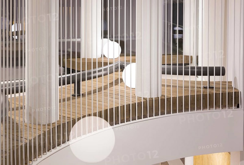 A modern club interior featuring sleek vertical white railings, wooden, and round white lights. The minimalist design offers a clean and sophisticated look