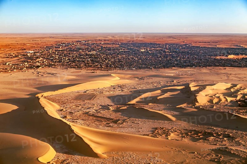 Desert town on the edge of the sand dunes, in the foreground extensive dune landscape, The dunes of the Endless Sahara from the air in Algeria