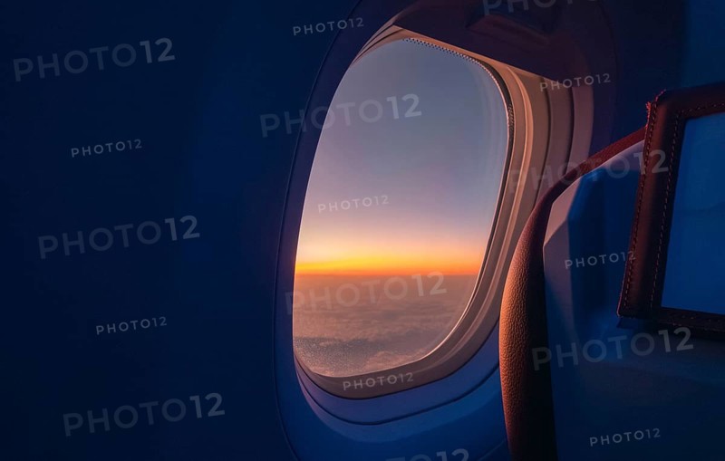 A breathtaking view of a sunrise from an airplane window, capturing the rich orange and blue hues blending over the horizon