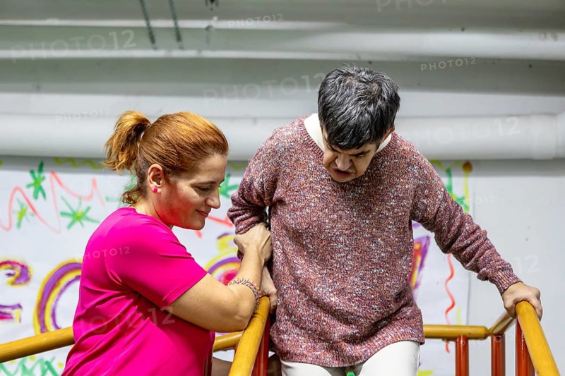 A compassionate caregiver assists a resident in a mental health facility, showcasing empathy and support. The setting emphasizes care and community involvement