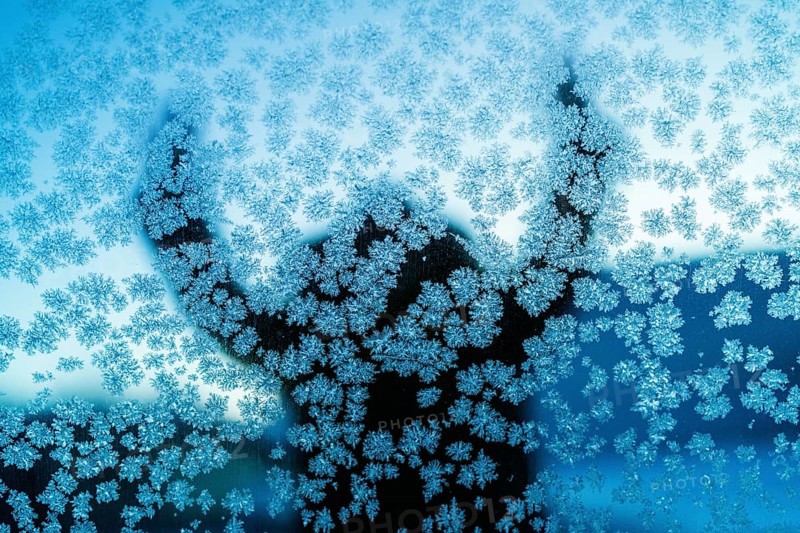 A captivating silhouette behind a frosty glass in Swedish Lapland, showcasing intricate ice crystal patterns on glass surface