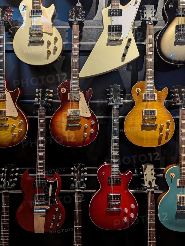 A collection of electric guitars displayed on a wall. Each guitar showcases a unique design and color, highlighting diversity in musical instruments