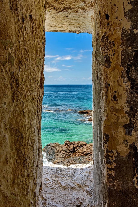 Sea of ??the city of Salvador in Bahia seen through a small window in a sentry box in the historic fort of Farol da Barra, Brazil