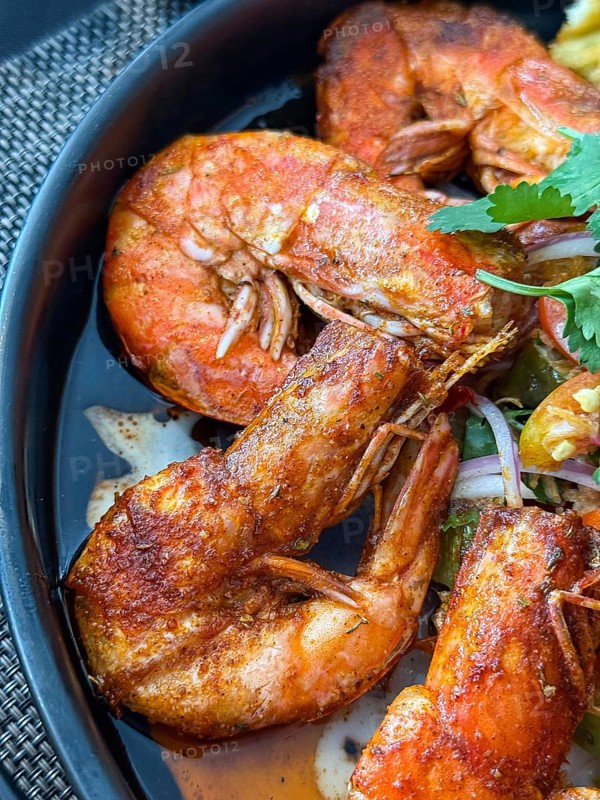 Close up of flavorful dish of seasoned fried shrimp served with a spicy dipping sauce in a Thai cafe setting
