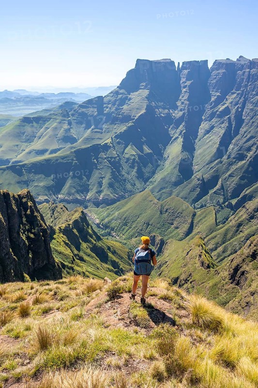 Young hiker looking at the impressive mountains and cliffs of the Drakensberg Mountains, hiking trail on the Sentinel Hiking Trail, Drakensberg, KwaZulu-Natal, South Africa