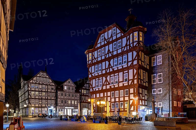Impressive half-timbered houses in their nocturnal splendour with lights on a quiet square, The historic town hall of Melsungen