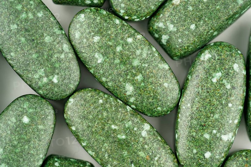 Close-up of green pills scattered on white background