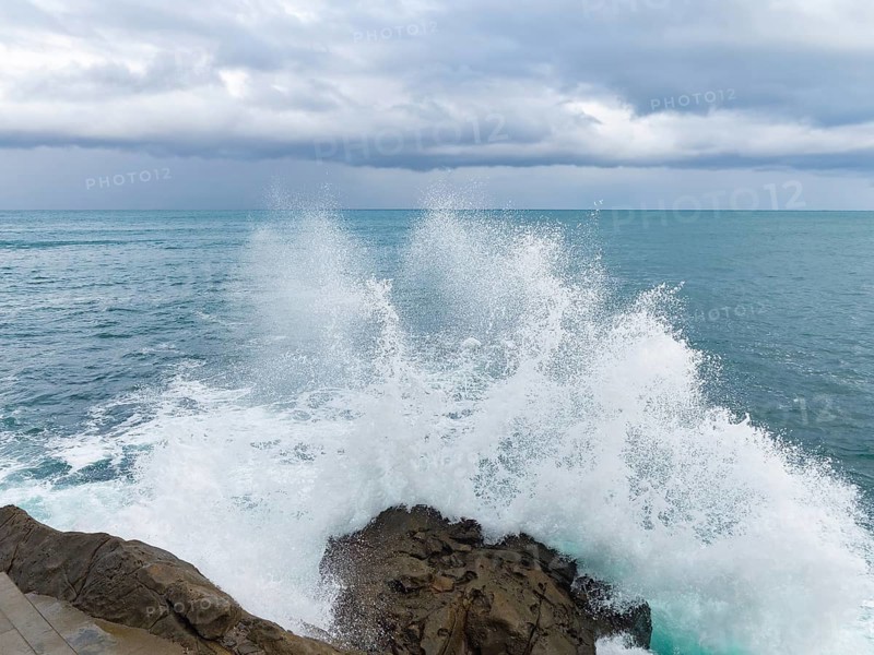 A dramatic scene as powerful waves collide with rugged rocks under a brooding sky, epitomizing the raw beauty of nature