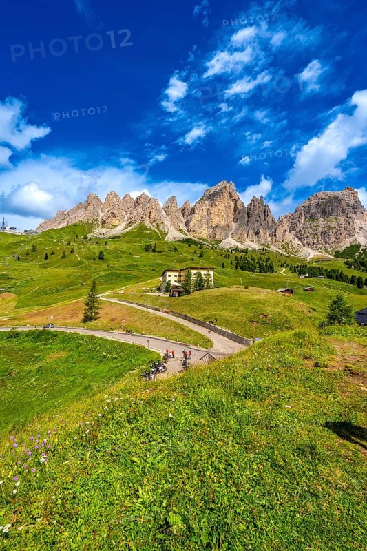 Bikers taking a break at gardena pass admiring the stunning view of the dolomites on a sunny summer day