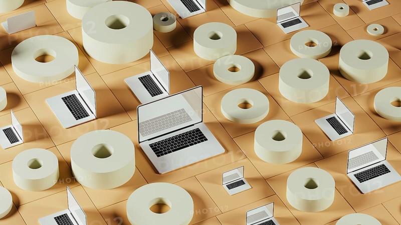 A collection of laptops placed among abstract geometric forms, showcasing a modern tech environment filled with creative design elements
