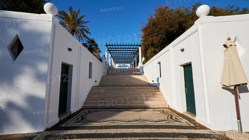 A wide staircase, flanked by white minimalist walls, leads to the top, surrounded by palm trees, Kalithea, Kallithea, thermal baths, thermal baths, bathing complex, Rhodes, Dodecanese, Greek Islands, Greece