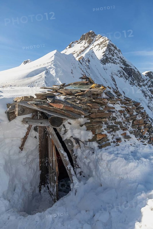 A rustic stone hut surrounded by snow against a majestic alpine backdrop. Ideal for ski touring enthusiasts seeking solitude and adventure in the wintry mountains