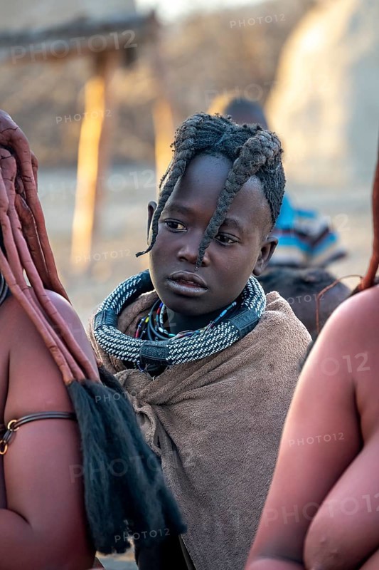 Himba girl, between Himba woman, portrait, in the morning, traditional Himba village, Kaokoveld, Kunene, Namibia