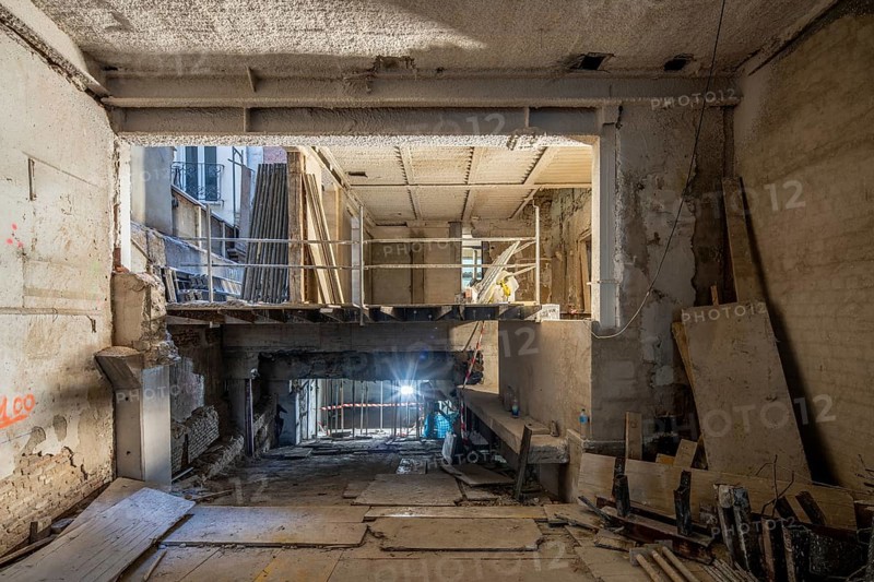 A construction site depicting an interior under renovation. Exposed beams, scaffolding, and building materials highlight the transformation process in progress
