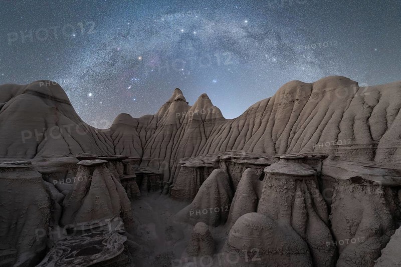 A serene night sky filled with stars illuminates the rugged, textured rock formations at a Utah, USA location, showcasing nature's beauty and the vastness of the cosmos