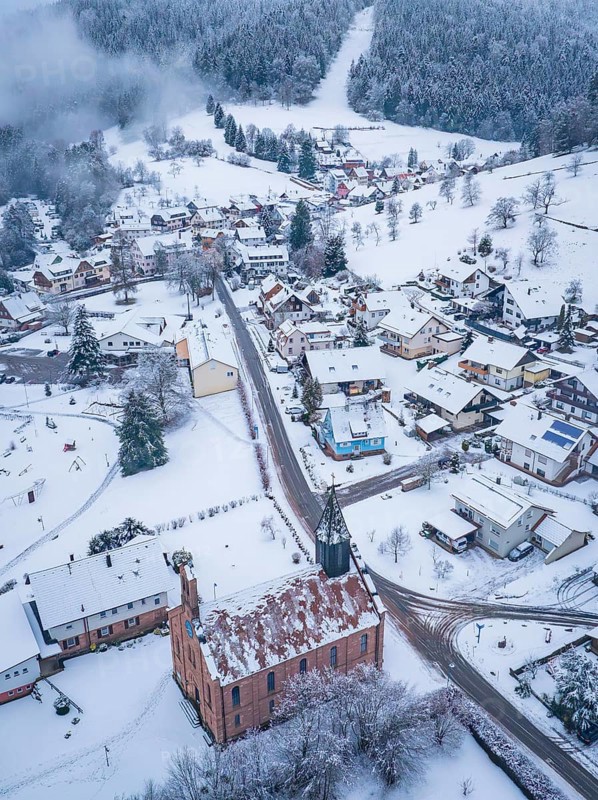 Snowy town view with church, surrounded by wooded hills, Enzklösterle, district of Calw, Black Forest, Germany
