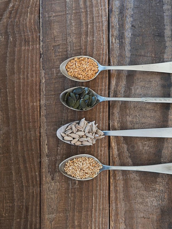 Various healthy seeds filling spoons on a rustic wooden background