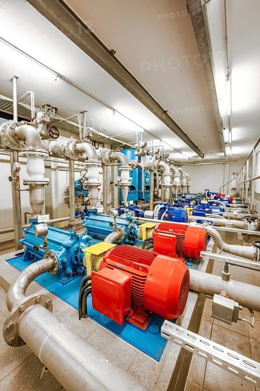 Machines with metal pipes and illuminated pumps in a technical room, ENCW Netze Calw waterworks, Calw, Black Forest, Germany