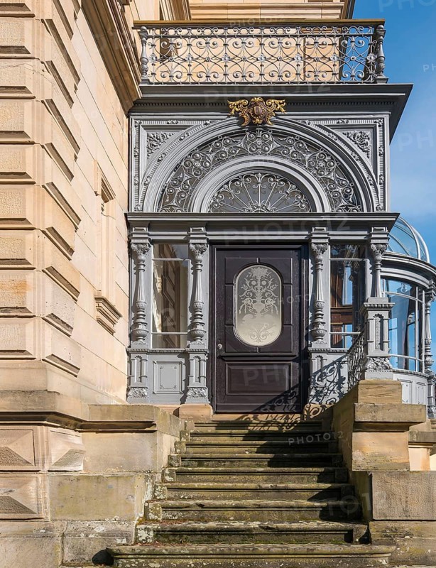 Historic door with filigree decorations and railings on a stone staircase in sunlight, Landau, Rhineland-Palatinate, Germany