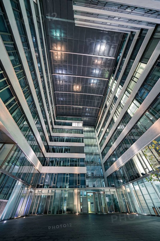 Modern building complex with illuminated inner courtyard and glass structure, Stuttgart, Germany
