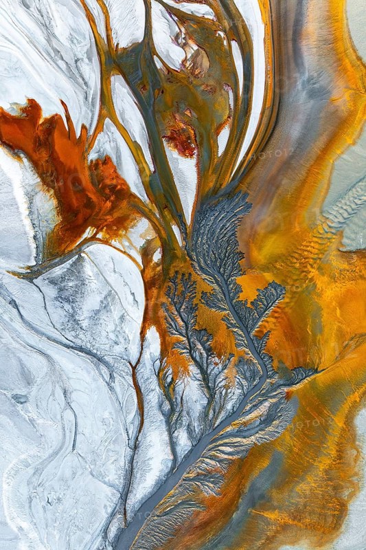 Intricate fractal patterns of vibrant mud textures create a stunning visual captured from above. Rich earthy tones blend, showcasing the complexity of natural formations