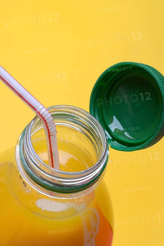 Orange juice in plastic bottle with cap and straw