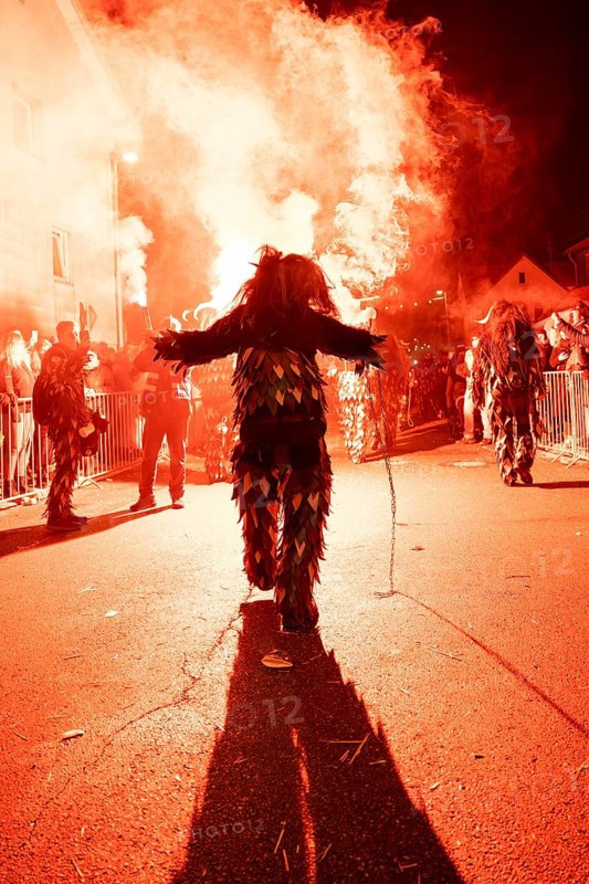 Impressive picture of a costumed participant during a nocturnal street party with glowing fire, carnival, Tiefenbronn, Enzkreis, Germany