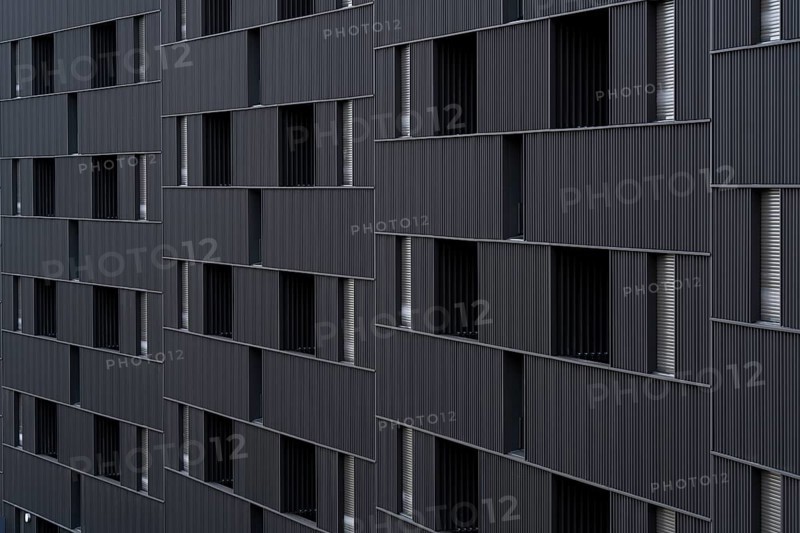 Modern building featuring a distinct, sustainable architectural style with vertically aligned, repeated portal-like window openings. The design emphasizes low-emission construction materials and efficient energy use