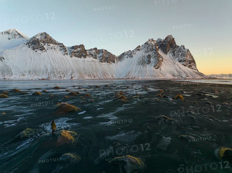 A stunning winter view of Stokksnes Beach in Iceland, featuring rugged snow-capped peaks against a tranquil twilight sky. Perfect for nature and travel themes