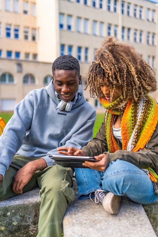 Millennial diverse student friends studying for an exam using digital tablet before going into classroom