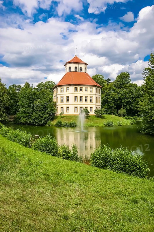Oppenweiler moated castle, built in the 18th century, classicist style, castle complex in unequal-sided octagon, today town hall, architecture, tent roof with pavilion top, windows, lake, castle lake, water features, island, park, garden designer Friedrich Ludwig von Sckell, meadow, lawn, trees, bushes, shrubs, cloudy sky, Oppenweiler, Rems-Murr district, Baden-Württemberg, Germany