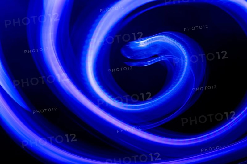 A mesmerizing abstract composition featuring swirling blue neon lights against a deep black background. The vibrant light trails create a dynamic, fluid effect