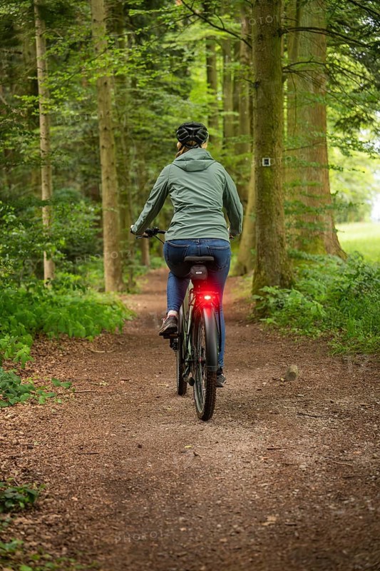 Person riding a bicycle in the forest. The surroundings are green and quiet, with a natural path, Bad Teinach, Black Forest, Germany