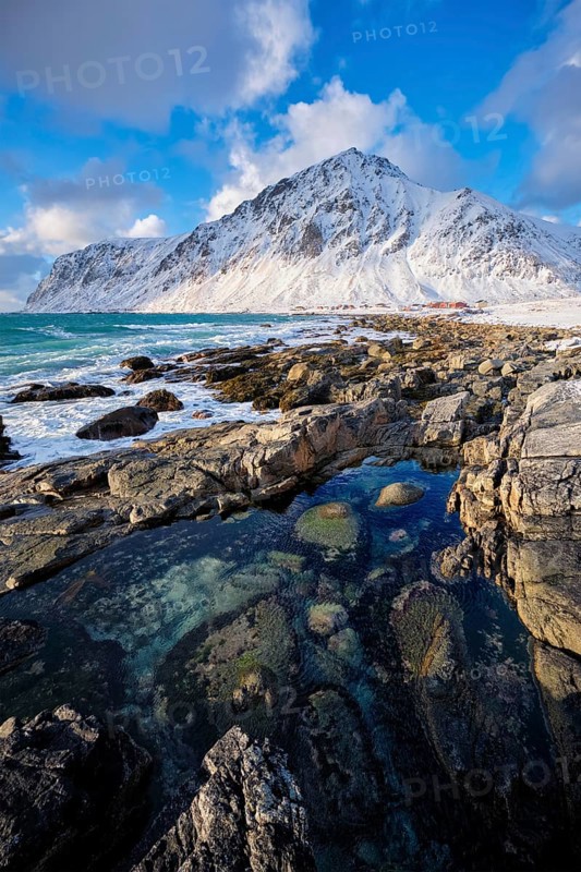 Beach of Norwegian sea on rocky coast in fjord on sunset in winter. Vareid beach, Lofoten islands, Norway