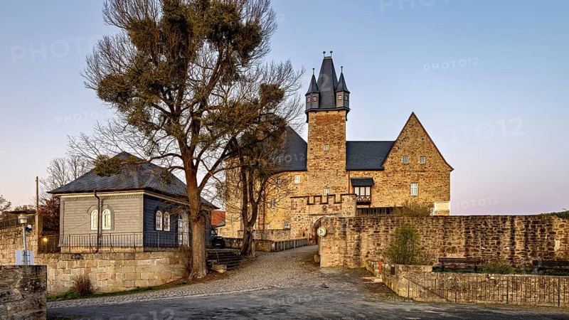 Evening view of a castle with courtyard, illuminated by warm light in front of sunset, Spangenberg Castle