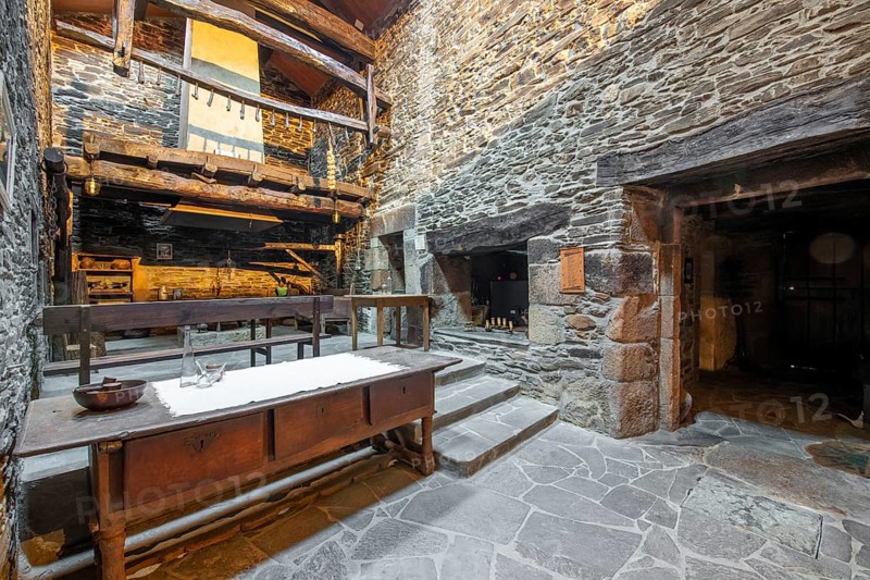 Rustic and traditional interior of a stone country house in Lugo, Spain, featuring a wooden balcony and vintage furnishings