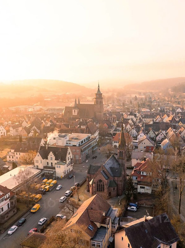 A church and a village in the evening light with a view of hills and trees, Weil der Stadt, Böblingen district, Germany