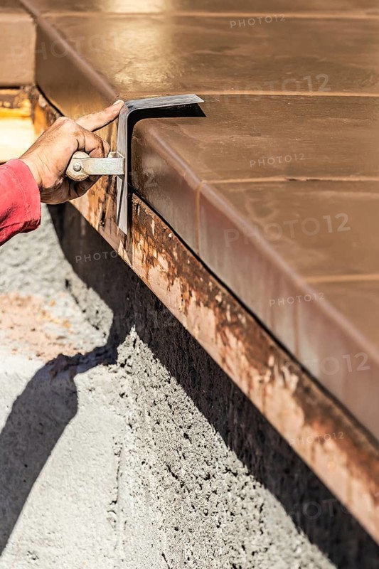 Construction Worker Using Stainless Steel Edger On Wet Cement Forming Coping Around New Pool