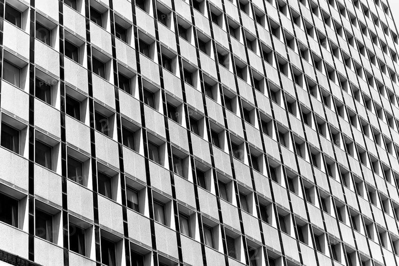 Black and white image of a building facade with repetitive square windows in Sidney, Australia. Captures the geometric symmetry and architectural design, highlighting urban aesthetic
