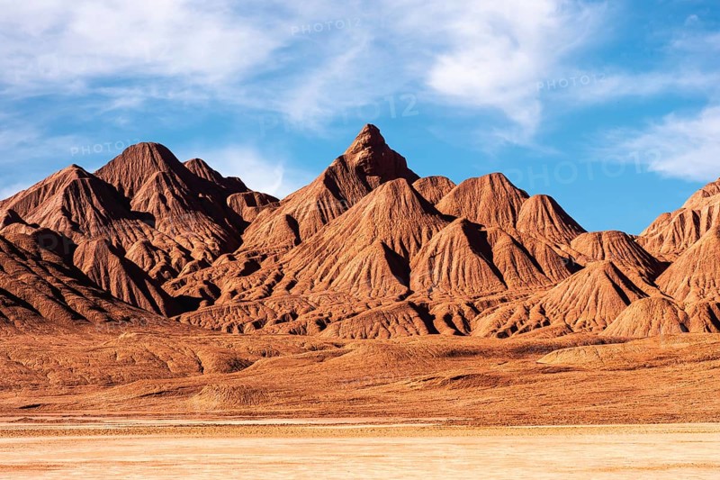 This image showcases the unforgiving terrain of Devil's Desert in Salta, Argentina. The sharp, rugged mountains stand prominently under a clear blue sky, highlighting the arid beauty of this distinctive desert landscape